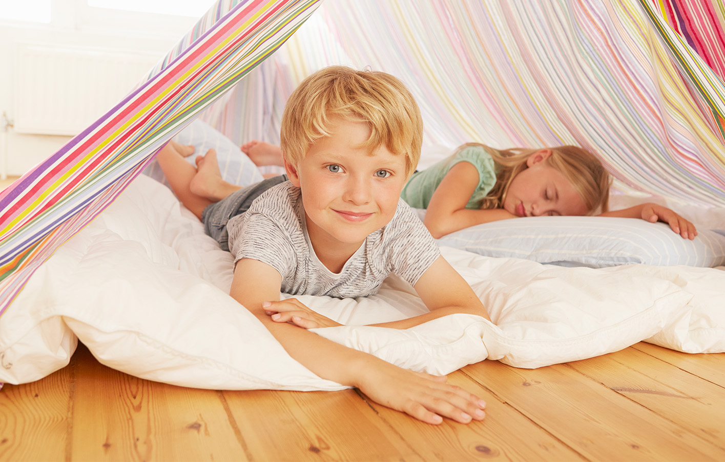 Holzboden als Spielfläche und Wohlfühlort für Kinder Kinder entspannen auf einem Holzboden und spielen in einer gemütlichen Wohnumgebung