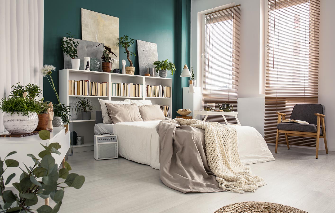 hellgrauer Laminatboden in einem Schlafzimmer mit einem hellem Bett und einer grünen Wand dahinter